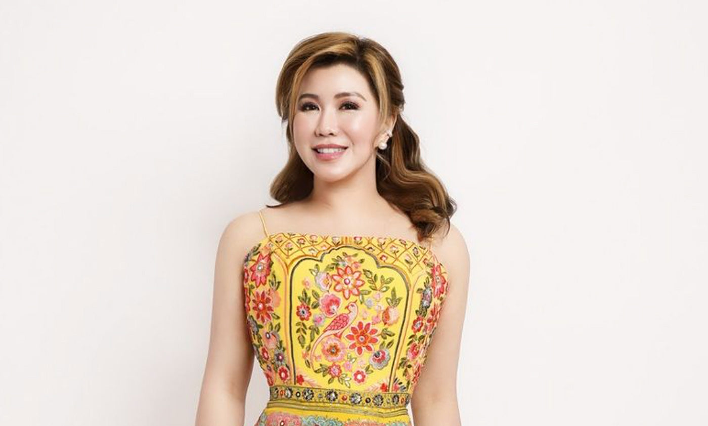 Olivia Quido smiling and wearing yellow floral dress