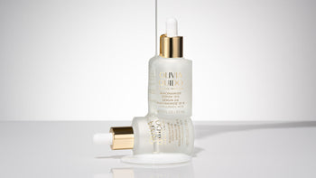 Olivia Quido Niacinamide Serum 10% sitting on top of another bottle of Niacinamide with serum dripping over