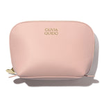 Olivia Quido Faux Leather Dome Cosmetic Bag in soft pink with gold logo, perfect for organizing travel essentials.