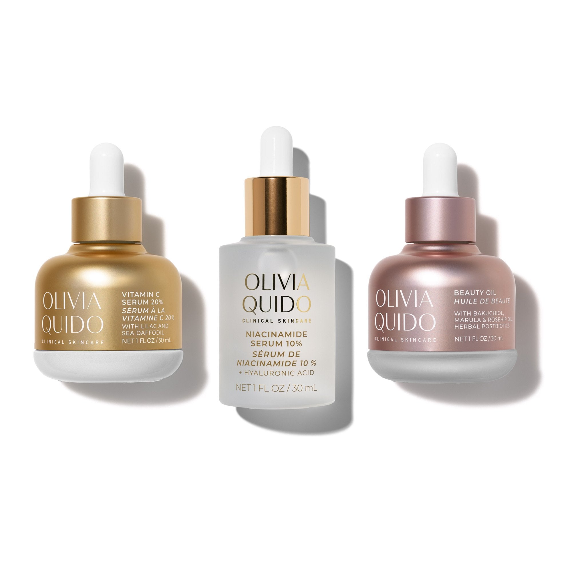 Three Olivia Quido skincare dropper bottles arranged side by side on a white background: a gold bottle labeled Vitamin C Serum 10%, a white bottle labeled Niacinamide Serum 10%, and a rose gold bottle labeled Beauty Oil 24oz.